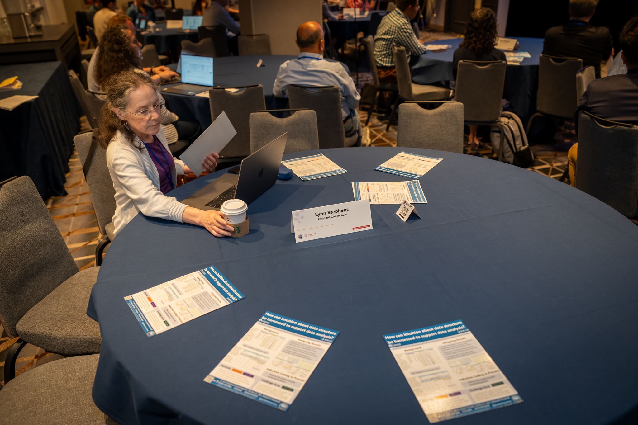 Women sitting at table with handouts around her. 
