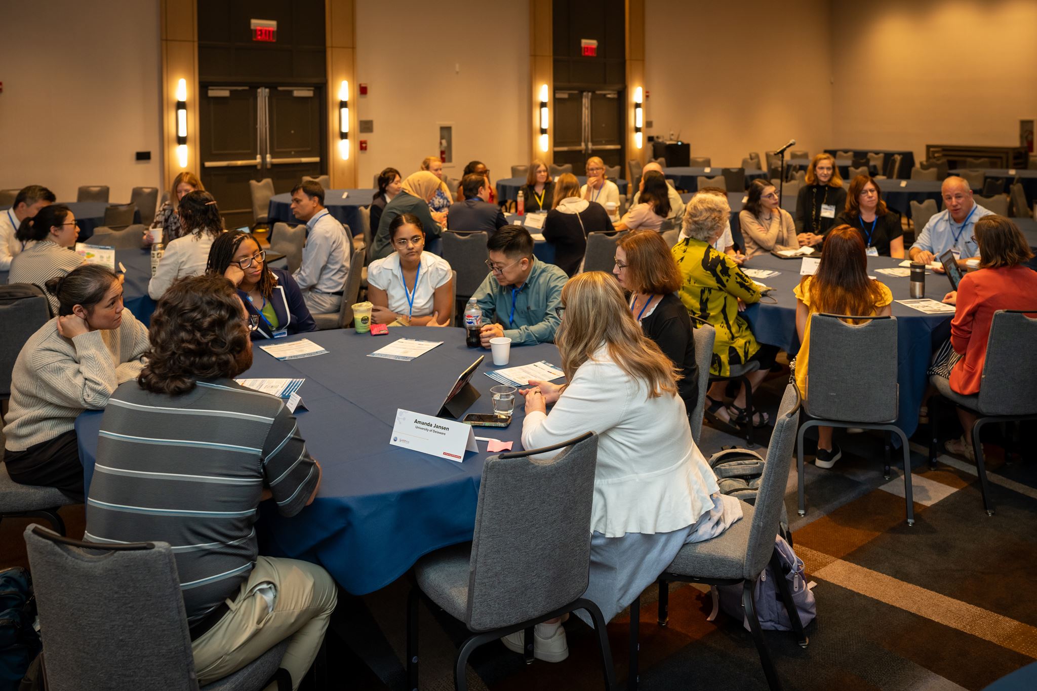 Multiple people sitting at the tables in a discussion. 